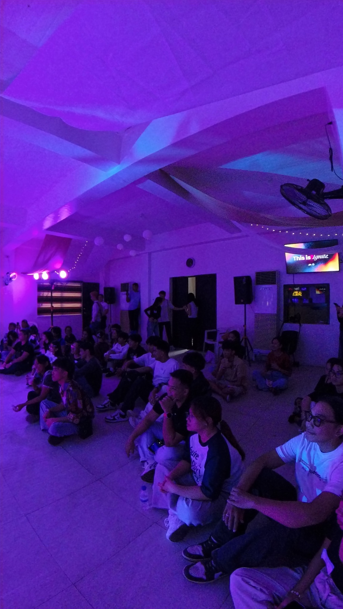 The Ignite 2025 audience sitting together under purple concert lights